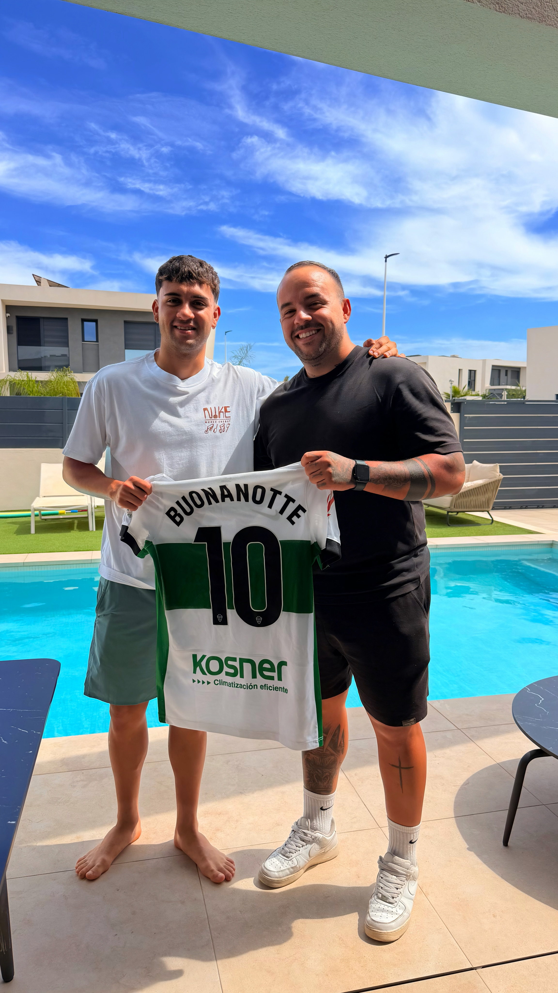 Dos personas mostrando una camiseta de fútbol al aire libre